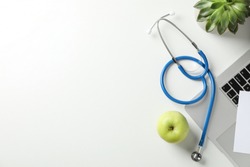 Stethoscope, apple, laptop and plant on white background, top view. Doctor workplace