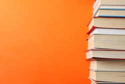 Stack of books on orange background, space for text
