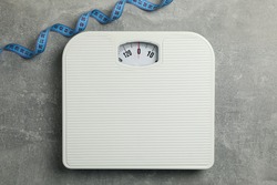 Scales and measuring tape on gray background. Weight loss concept