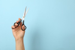 Female hand holds hairdresser scissors on blue background