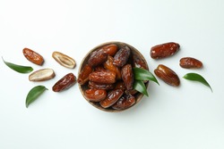 Bowl of dried dates with leaves on white background