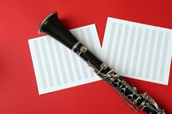 Clarinet and music sheets on red background.