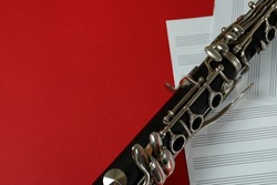 Clarinet and music sheets on red background.