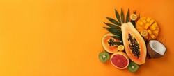 Exotic fruits set on orange background, space for text.