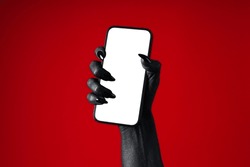 A black hand holds a phone, on a red background.