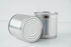 Two aluminum closed metal cans on a white table. 