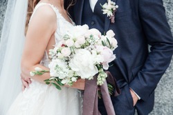 bride holding a bouquet of flowers in her hand, the groom embracing her
