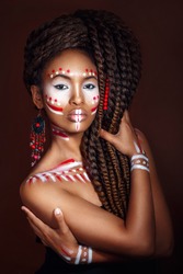 African style woman . Attractive young woman in ethnic jewelry with drum. close up portrait. Portrait of a woman with a painted face. Creative makeup and bright style.