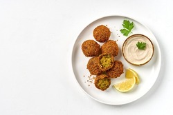 Plate of chickpeas falafel with tahini sauce isolated on white background. Top view, copy space