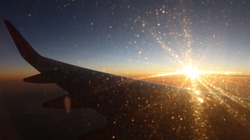 Orange sunset from airplane window with small soft bokeh and realistic sun rays.