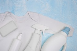 White bodysuit without stains and different types of stain removers. Dirty clothes. Stubborn stains. Clean linen, bleach, yellowness of white. Soap, liquid bleach, spray bottle, household chemicals.