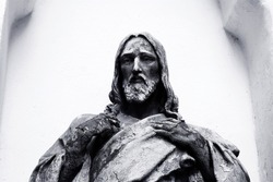
black and white statue of jesus with cracks in his arms he looks into the distance and presses his arms to his chest