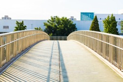 Concrete bridge with metal railing. Curved foot bridge. Street photo.
