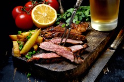Steak with herbs and beer on a wooden background