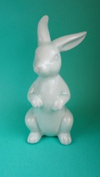 close-up ceramic figurine of a blue Easter bunny on a turquoise background front view . Easter symbol