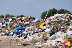 Big pile of unsorted garbage under the sun in municipal landfill in summer day, selective focus