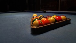 Pool game sport on green cloth.  Multi-colored billiard balls in triangle shape with numbers, two cues, cue balls and triangles on the pool table.  Billiards billiard ball close up.