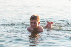 Happy smiling boy having fun swimming in the water.Cute kid swimming in water. Boy having fun at the beach. Summer vacation. Active lifestyle concept. Happy kid on summer vacations.