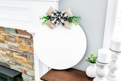 Blank round white wood sign with buffalo plaid bow on brown shelf, welcome door sign mockup