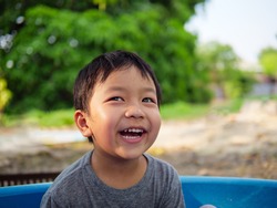 Asian cute child boy smiling and laughing with whitening teeth in nature background with thinking, funny face in relaxing day. Concept of healthy lifestyle, happy expression.
