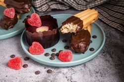 Valentinesday cupcake. Dark chocolate coated digestive biscuit . Sweet delicious dessert truffle and heart shaped candy on a plate. Dark Background with Copy space.