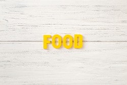 The sign, word food on a white wooden background, top view. Children colored plastic letters.
