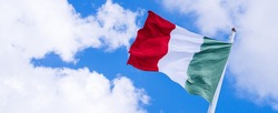 Waving Italian flag on a clear sky with some clouds