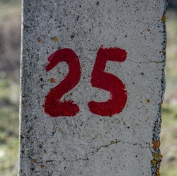 Number 25 painted with red paint on gray concrete.Abstract writing number 25 on concrete. Quarter symbol.25 percent discount. Concrete numbers.Number 25 on the wall