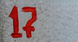 Parking number 17 with screen paint on concrete.red number 17 is written with a brush on concrete.