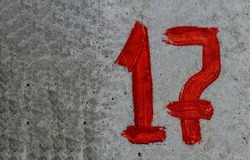 Parking number 17 with screen paint on concrete.red number 17 is written with a brush on concrete.