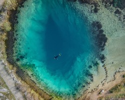 Extreme sport: One person diving the blue hole Izvor Cetine, Dalmatia. Aerial top down shot in April, 2021.