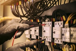 Close-up hand of electrical engineer using measuring equipment to checking electric current voltage at circuit breaker and cable wiring system for maintenance in main power distribution board.
