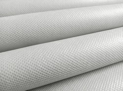 rolled white polypropylene fabric. non-woven fabric background with fibrous texture. industrial bag material