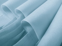 light blue polypropylene bag. non-woven fabric with wavy pleats. pile of environmentally friendly bag materials. spunbond bag