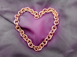 heart-shaped gold metal chain on the surface of faded purple cloth
