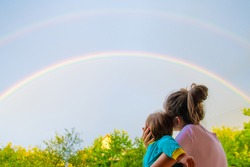 Mom with a child looks at the rainbow. Mom and son on the background of motherhood. Look at the rainbow.