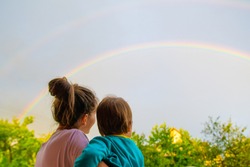 Mom with a child looks at the rainbow. Mom and son on the background of motherhood. Look at the rainbow.