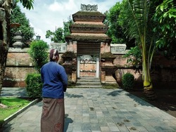 A man in traditional Javanese clothes standing on the graveyard before the gate of Mataram kings cemetery in Yogyakarta, Indonesia