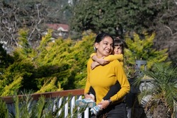 A mother, woman, female, girl playing, cuddling, smiling, hugging, holding  cute beautiful lovely girl, child, kid, daughter in a garden, vacation, place, hotel, hill station, picnic. Single mother.