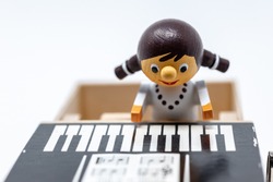 A small wooden girl in a wind up toy piano