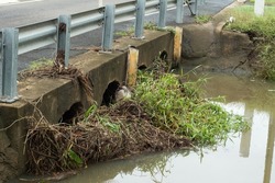 Flood debris blocking water flow through the pipes under of a small bridge Baldwin swamp in Bundaberg.