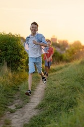 Cute smiling young boy running forward along the countryside pathway in summer. Happy childhood concept
