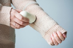 Pilled sweater. Woman wearing an old sweater with lint (pilling). Woman use handheld electric fabric shaver fuzz remover device machine for removing fuzz, lint and pills on clothes