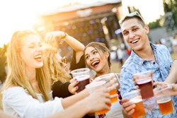 Friends drinking beer and having fun at music festival 