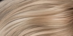 A closeup view of a bunch of shiny straight blond hair in a wavy curved style.