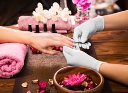 Closeup finger nail care by manicure specialist in beauty salon. 