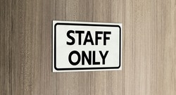 Warning silver stainless steel sign with character black message staff only in front of the wooden door