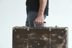 A man with an old suitcase in his hand. Wedding ring on the ring finger. Close-up. Unsuccessful family life concept.