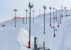 Ski mountain with ski cross track element, surface lift, lighting towers. Winter freestyle skiing competition concept.