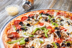 A view of a meat and veggie pizza pie, in a restaurant or kitchen setting.